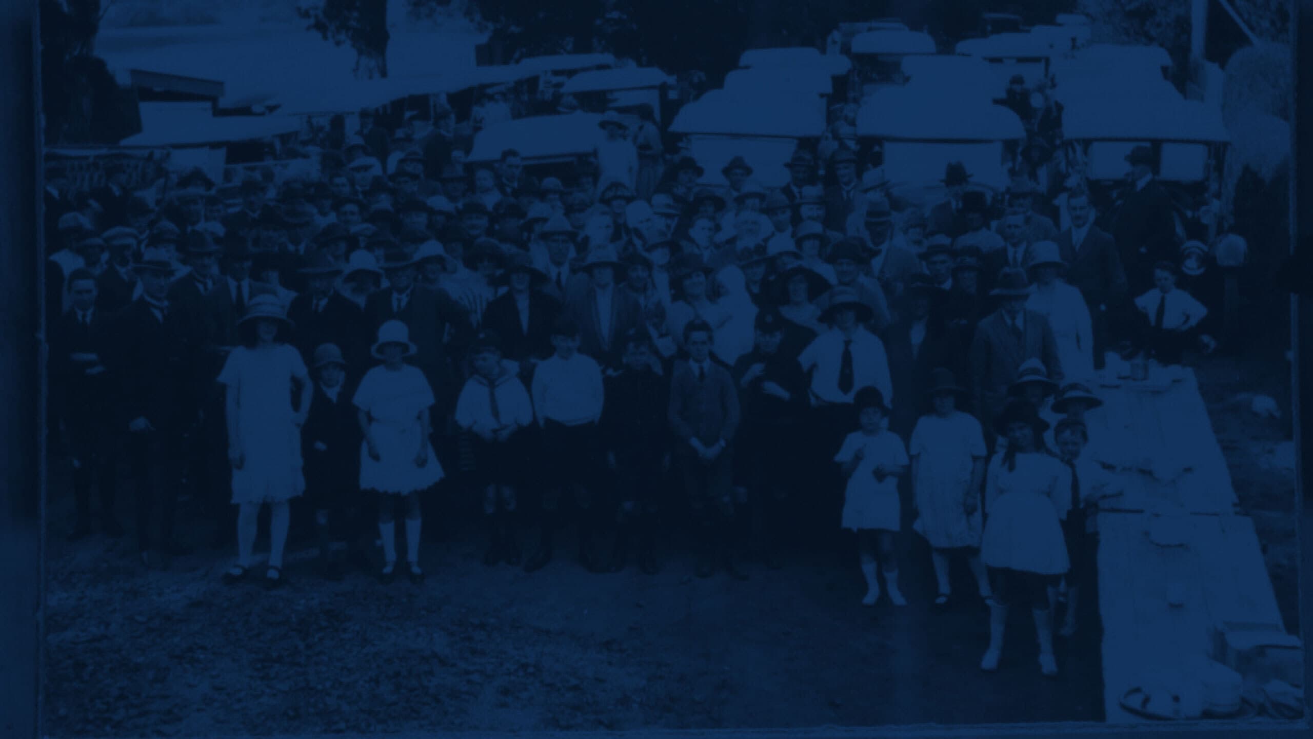 Vintage photo of people gathered in front of cars